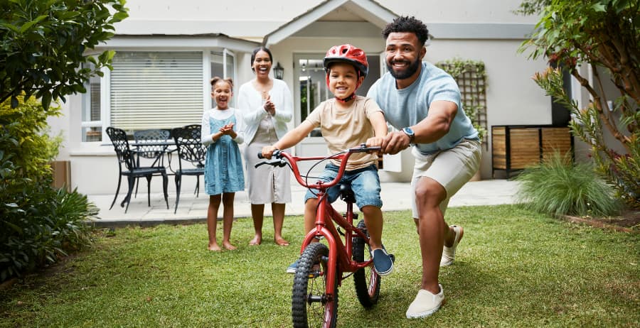 Kid learning to ride a bicycle at his home with family